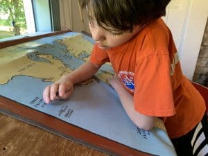A boy looks at a map of the world and dreams of what he will be when he grows up