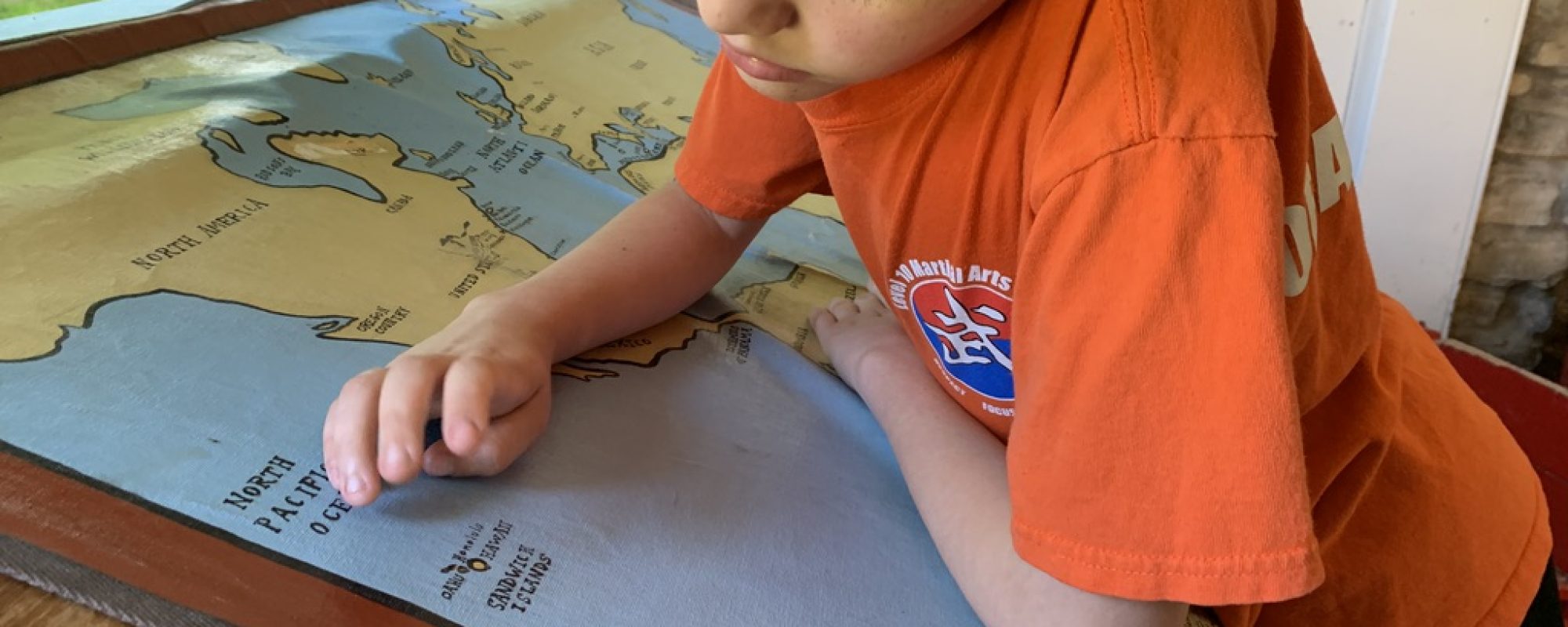 A boy looks at a map of the world and dreams of what he will be when he grows up
